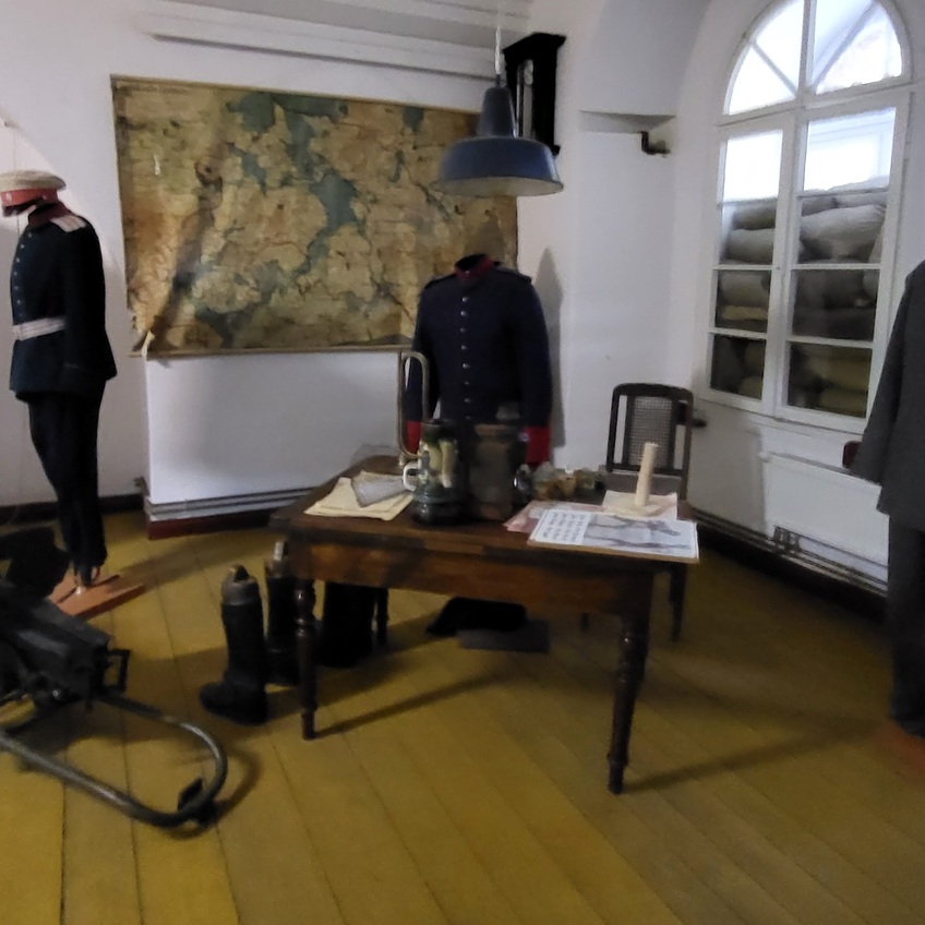 Mazurska Pętla Rowerowa: wnętrze Twierdzy Boyen z mundurami, stołem sztabowym i mapą regionu.